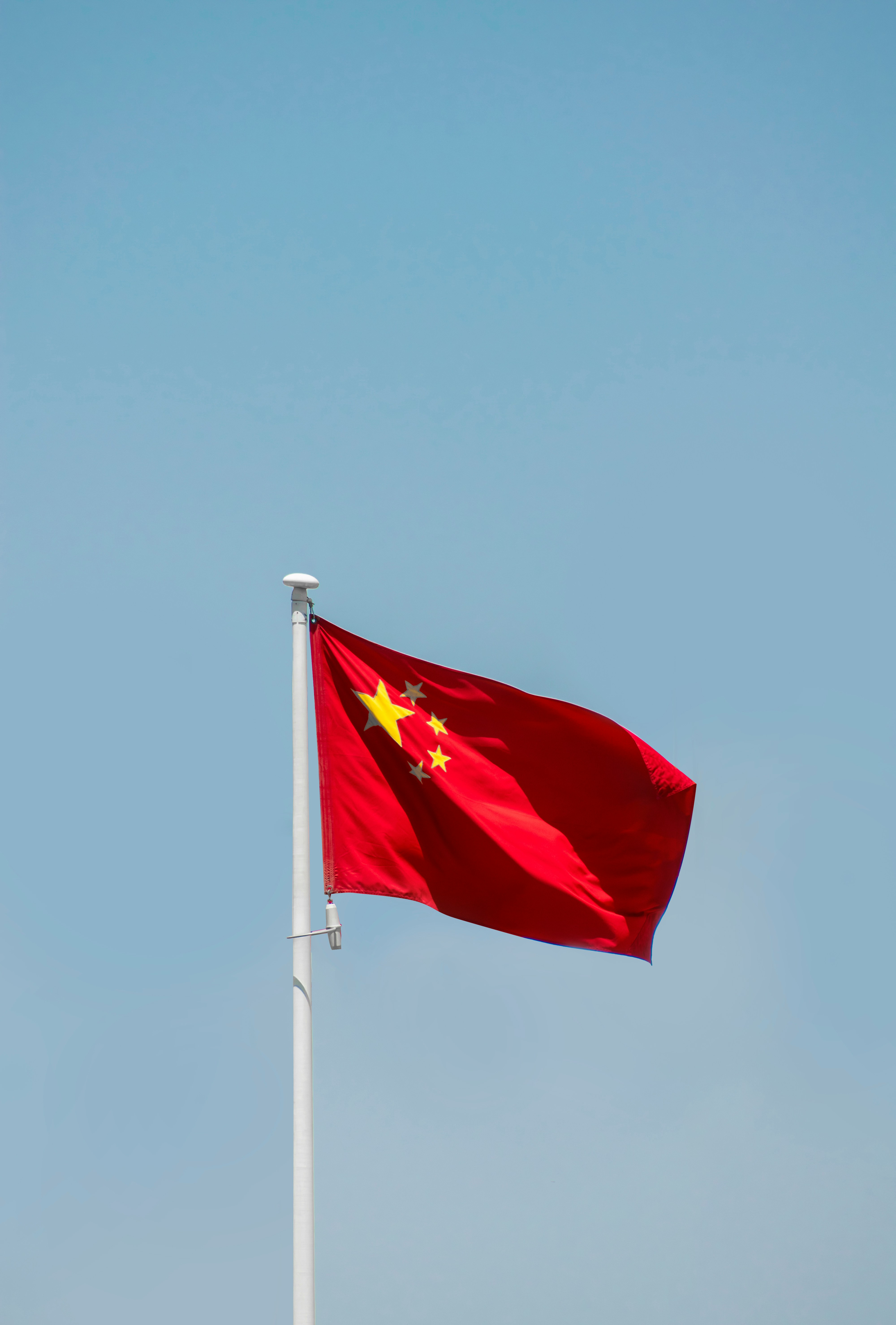 The red national flag of the People’s Republic of China waving against a clear sky, symbolizing Chinese geopolitical influence and state presence central to the Philippines–China dispute over the South China Sea.