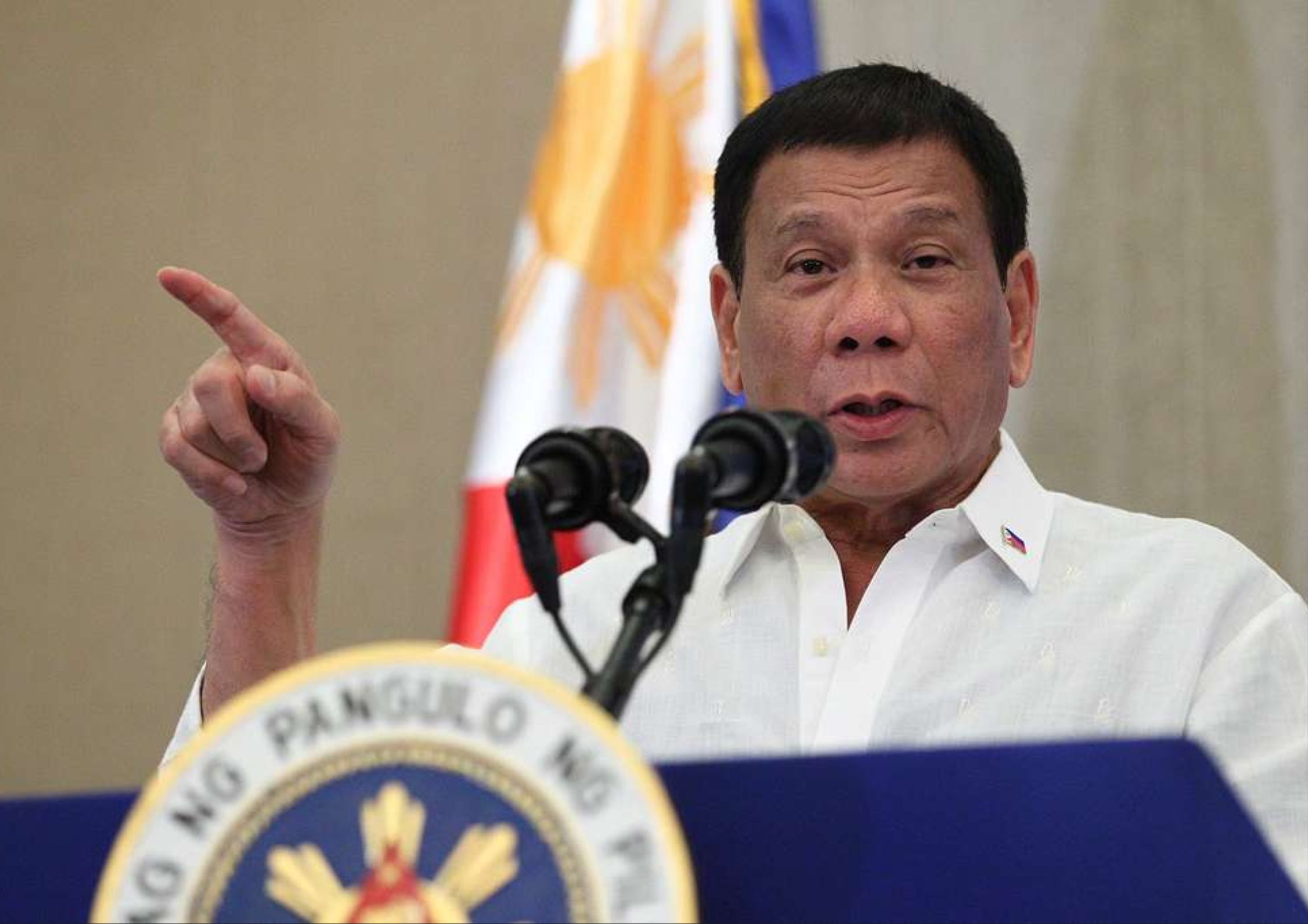 Former Philippine President Rodrigo Duterte speaking at a podium with the presidential seal, captured mid-speech in front of the Philippine flag—highlighting his central role in the ICC trial for alleged crimes against humanity during his war on drugs.